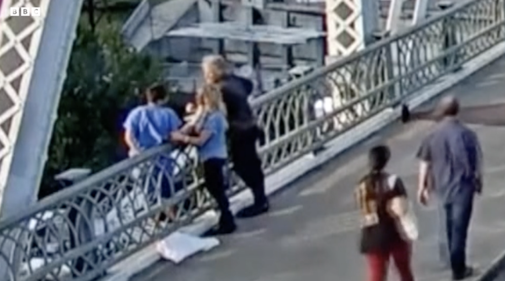 Jon Bon Jovi and friend talking to a woman standing on a bridge's railing